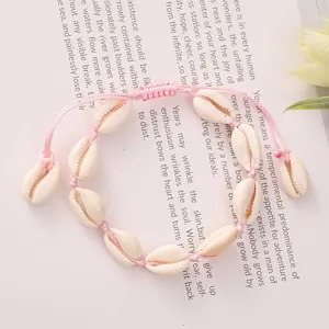 Detail view of handmade pink woven cowrie shell bracelet for summer beach vacations.