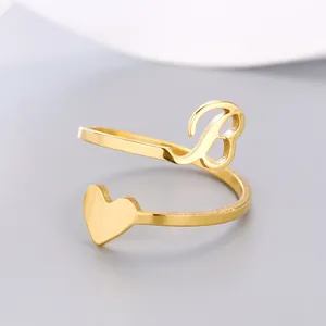 Close-up detail of golden stainless steel open ring with initial B and heart charm.