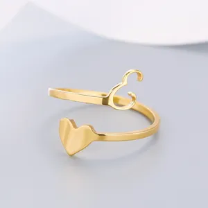 Close-up of a gold stainless steel heart ring with letter C detail on grey background