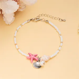 Detailed macro view of white beaded bracelet featuring starfish and shell charms