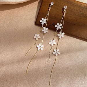 Close-up of elegant long tassel earrings with delicate white flowers and studs