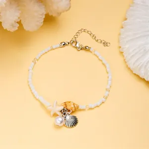 Detailed close-up view of the starfish and shell charms on a white seed bead bracelet