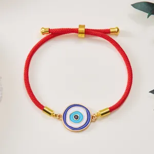 Macro detail of adjustable red string bracelet with blue Evil Eye charm and gold accents