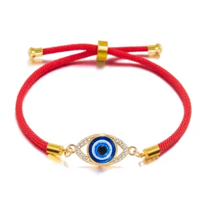 Macro detail of red cord drawstring bracelet with sparkling rhinestone evil eye charm