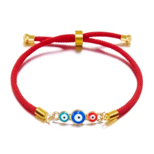 Detailed macro view of the adjustable red rope and three Evil Eye enamel charms