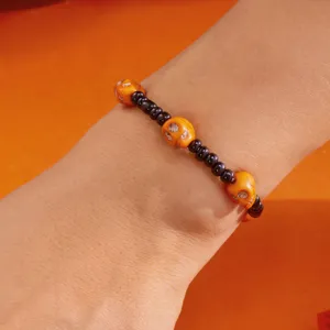 Pulsera de cuentas hecha a mano para Halloween con calaveras naranjas en la muñeca