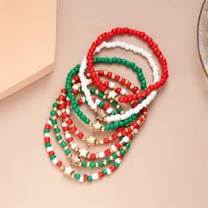 Primo piano di 7 braccialetti natalizi con perline e ciondoli a stella rossi e verdi.