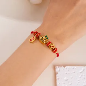 Détail d'un bracelet en corde tressée rouge avec un pendentif en forme de serpent doré