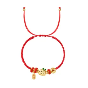Détail d'un bracelet tressé rouge avec pendentif serpent doré et étiquette de chance 2025
