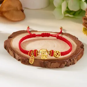 Vue détaillée d'un bracelet tressé rouge avec breloque cochon dorée et pendentif porte-bonheur