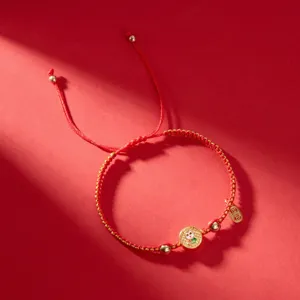 Détail du bracelet tressé rouge avec pendentif serpent doré pour l'année 2025