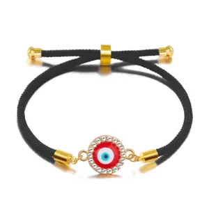 Close-up of a red evil eye charm on an adjustable black braided cord bracelet