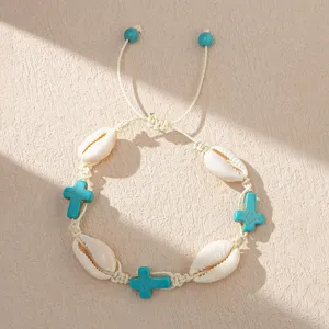Macro detail view of Bohemian shell bracelet featuring turquoise crosses and woven cream cord