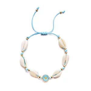 Close-up of bohemian shell bracelet featuring cowrie shells and a blue daisy charm detail