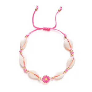 Close-up of pink woven shell bracelet with enamel flower charm on white background