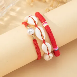 Close-up of bohemian shell and red beaded bracelet set for summer beach vacation style