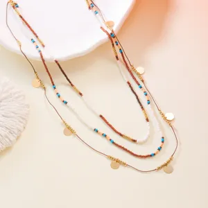 Detailed macro view of bohemian 3-piece beaded necklace set with gold coin charms and colorful beads