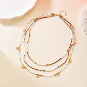 Close-up detail of bohemian multi-layered beaded necklace with gold disc charms