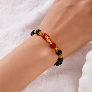 Close-up of a beaded zodiac snake bracelet featuring gold, red, and black beads on a wrist