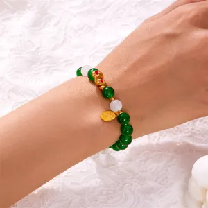 Close-up detail of a Year of the Snake beaded bracelet with green stones and gold charms