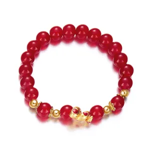 Detailed macro view of red beaded bracelet featuring a golden zodiac snake charm for 2025