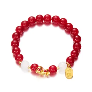 Close-up of red and white beaded bracelet with gold snake charm and blessing tag