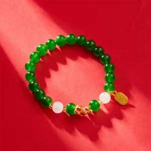 Close-up of green beaded bracelet with golden zodiac snake charm for luck