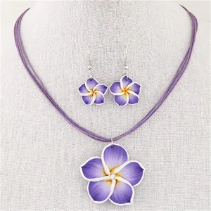 Nahaufnahme eines lila Frangipani-Halsketten- und Ohrring-Sets auf einer weißen Büste