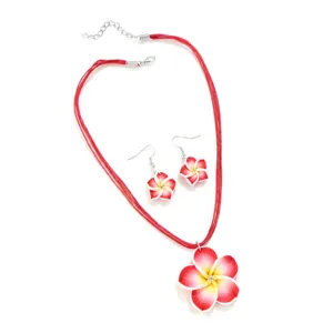 Nahaufnahme eines lebhaften roten Frangipani-Halsketten- und Ohrring-Schmucksets