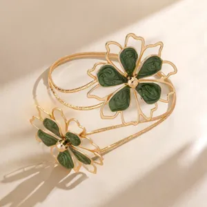 Close-up van een gouden holle armring met groene gemarmerde emaille bloemen