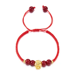 Vue détaillée d'un bracelet tressé rouge avec breloque serpent dorée et perles rouges