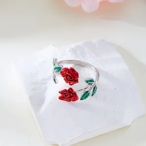 Detailed view of an elegant silver open ring featuring red enamel roses and green leaves