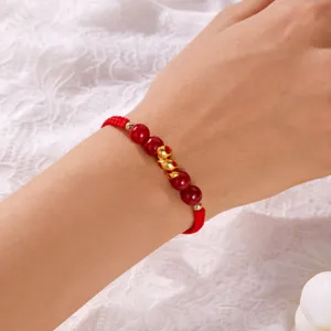 Gros plan d'un bracelet tressé rouge avec perles de cinabre et pendentif serpent doré