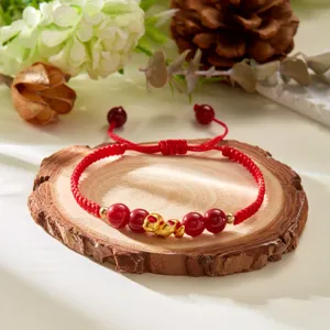 Vue détaillée d'un bracelet tressé rouge fait main avec une breloque serpent dorée pour 2025.