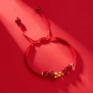 Détail du bracelet tressé rouge de l'Année du Serpent 2025 avec petit pendentif doré.