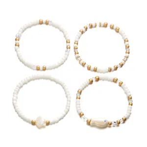 Elegante juego de 4 pulseras de cuentas blancas y doradas con dijes de concha y de pez