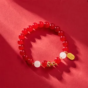Close-up of 2025 Year of the Snake red beaded bracelet with lucky gold charm