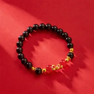 Year of the Snake beaded bracelet with gold snake charm and black beads on red background.