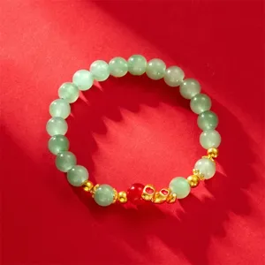 2025 Year of the Snake green bead bracelet with gold-tone charm on red background