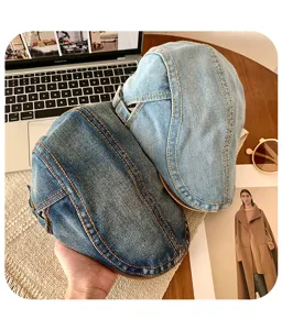 Washed denim krantenjongenspet detailweergave, licht- en donkerblauw met contrasterende stiksels.