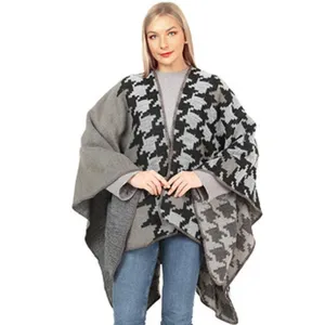 Vista detallada de una mujer que luce un poncho de punto de pata de gallo gris