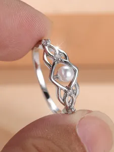 Detailansicht eines eleganten silberfarbenen Ringes mit Perle und filigranem Design