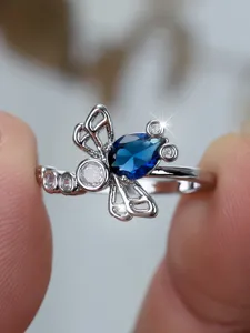 Primo piano di un anello a libellula con zircone blu a goccia e pietre chiare