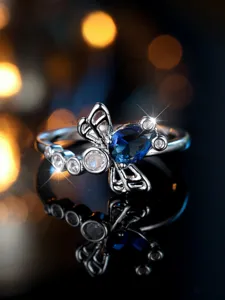 Primo piano di un anello a libellula vintage con pietra blu a goccia e ali traforate