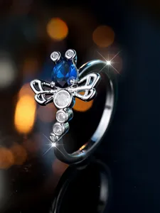 Macro di un anello vintage a forma di libellula con zircone blu a goccia e dettagli incisi