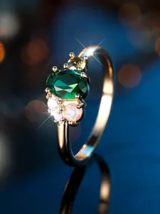 Macro detail of luxury golden ring featuring a green oval stone and mosaic opal inlay