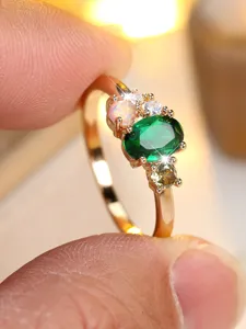 Detailed close-up of a gold ring with oval green gemstone and pink opal stones.