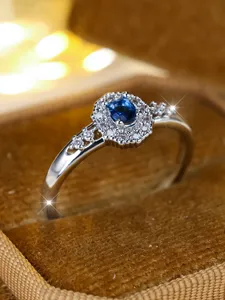 Nahaufnahme eines silbernen Rings mit blauem Zirkonia und doppeltem Diamant-Halo