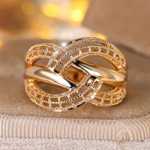 Detailed macro shot of a gold woven ring with an intricate crossover texture pattern.