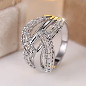 Close-up detail of a silver-colored hollow woven crisscross ring with sparkling stones